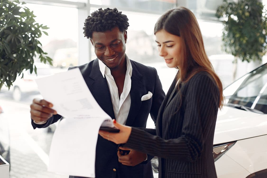 Two professionals reviewing a written agreement in a car showroom